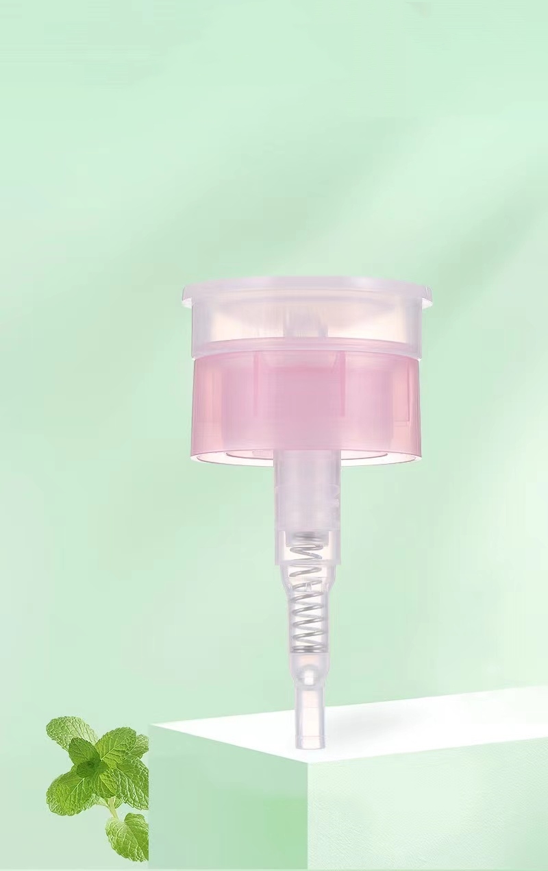 Pink and transparent pump dispenser with mint leaves on green background.