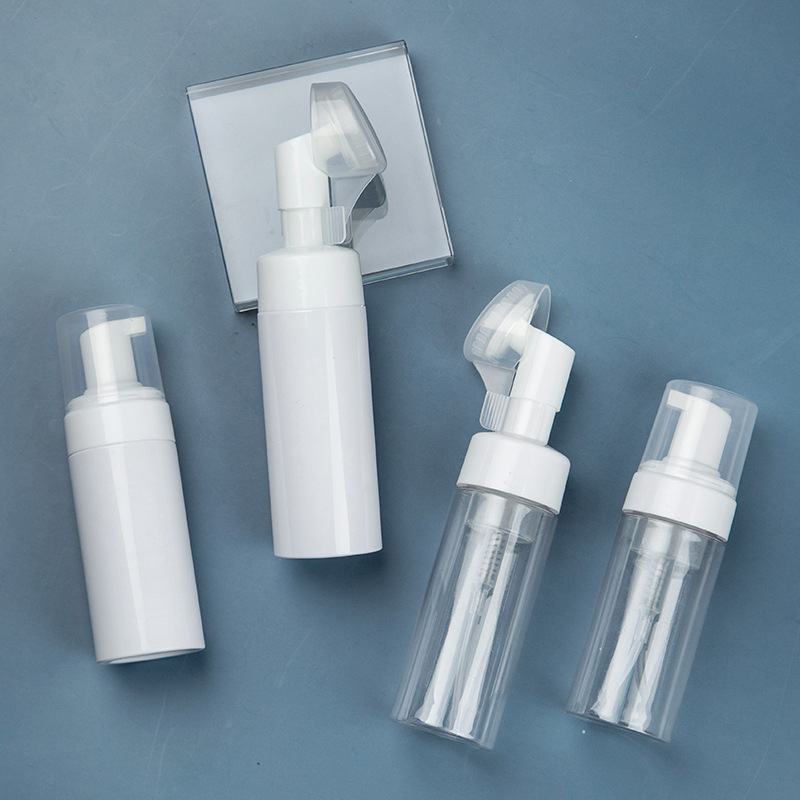 Four white and transparent foam pump bottles arranged on a blue background.