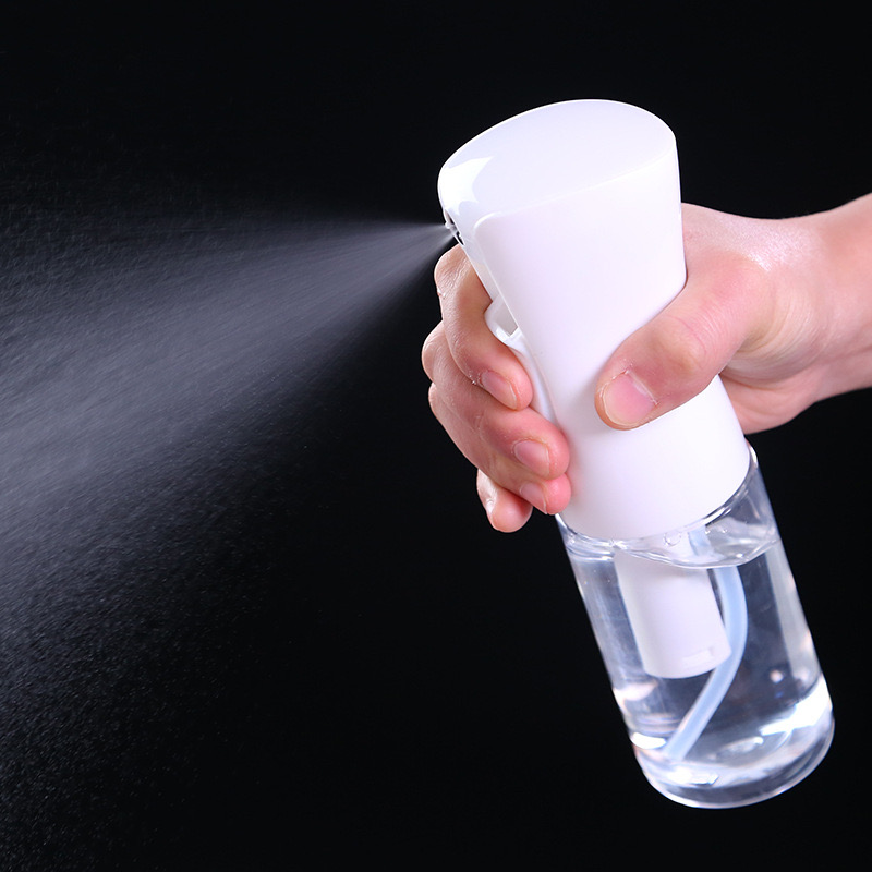 Hand pressing a white spray bottle with clear liquid, releasing a fine mist.